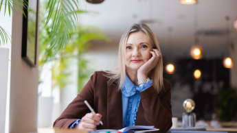 Brain2Business Academy - neuronauka w przywództwie i zarządzaniu | Uniwersytet WSB Merito Warszawa: Uśmiechnięta studentka z długopisem w dłoni.