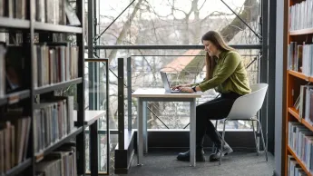 Prawo spółek i nadzór właścicielski | Uniwersytet WSB Merito Warszawa: Studentka pracująca w bibliotece.