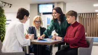 Polityka wynagrodzeń i wartościowanie stanowisk w świetle nowych regulacji UE | Studia podyplomowe w Warszawie | Uniwersytet WSB Merito Warszawa: Ludzie przy stole rozmawiają o studiach.