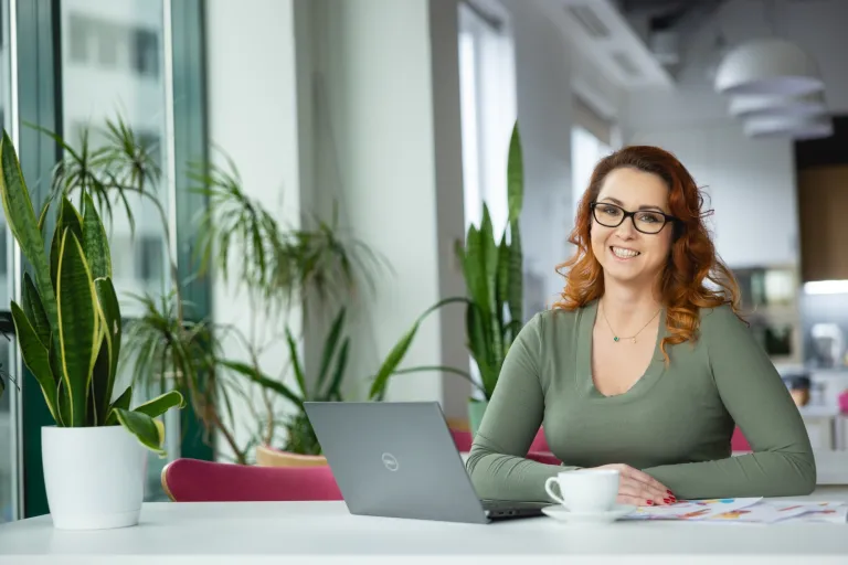 Programista Python Developer | Studia podyplomowe w Warszawie | Uniwersytet WSB Merito Warszawa: uśmiechnięta kobieta siedząca przy laptopie
