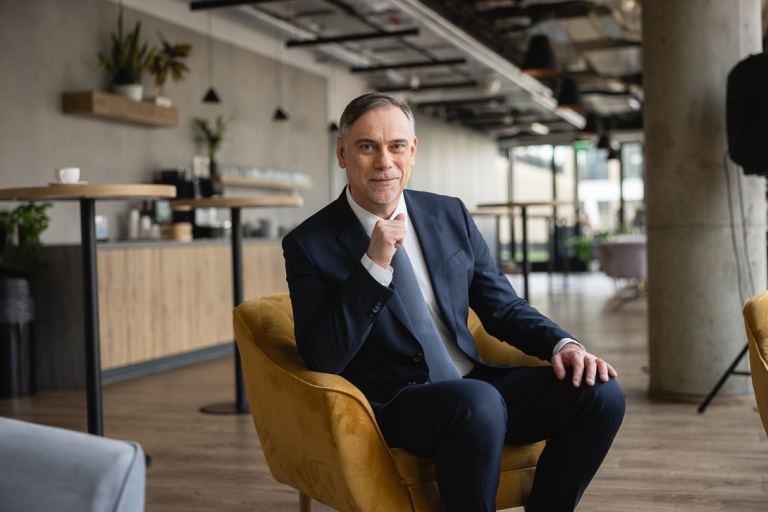 MBA HR | Studia MBA w Warszawie | Uniwersytet WSB Merito Warszawa: Uczestnik studiów MBA pozuje na fotelu na korytarzu- Uniwersytet WSB Merito Warszawa