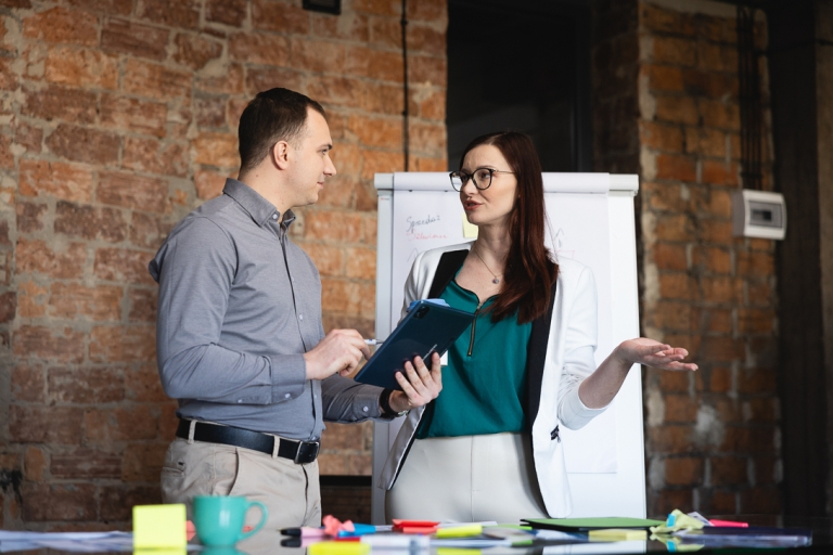 Kadry i płace | Studia podyplomowe w Warszawie | Uniwersytet WSB Merito Warszawa: mężczyzna z kobietą rozmawiający na temat projektu