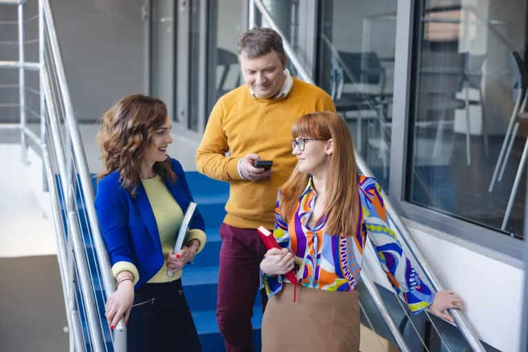 Customer experience i zarządzanie relacjami z klientem | Studia I stopnia w Warszawie | Uniwersytet WSB Merito Warszawa: trójka osób rozmawiająca ze sobą na schodach