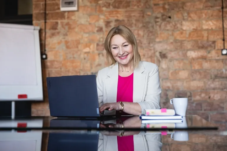 Twoja innowacja, Twoje zasady. Jak chronić projekty w sektorze EduTech? | Aktualności | Uniwersytet WSB Merito Warszawa: uśmiechnięta kobieta patrząca w ekran laptopa