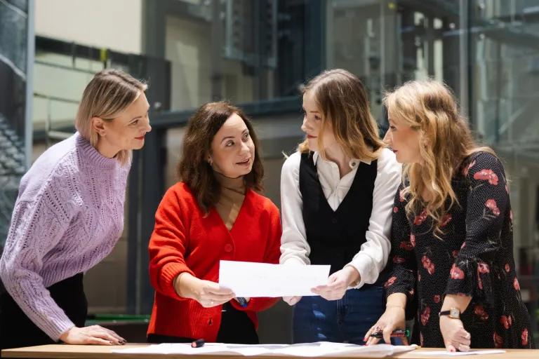 Public relations i wizerunek w erze cyfrowej | Studia I stopnia w Warszawie | Uniwersytet WSB Merito Warszawa: Ludzie omawiają projekt nad stołem.