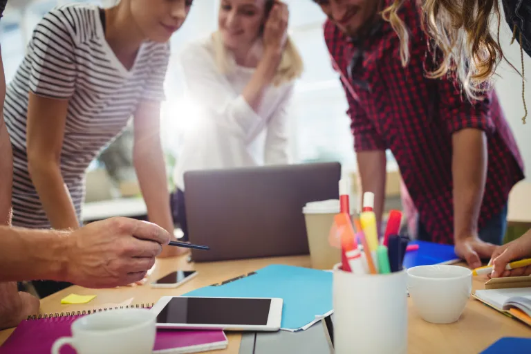 Cloud DevOps Engineer Administrator | Studia podyplomowe we Wrocławiu | Uniwersytet WSB Merito we Wrocławiu: Grupa osób pracująca przy stole z zeszytami i długopisami
