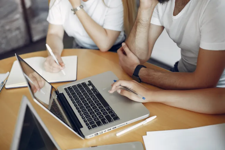 Business Intelligence & Information Management | Studia podyplomowe we Wrocławiu | Uniwersytet WSB Merito we Wrocławiu: Grupa osób pracuje wspólnie przy laptopie, zapisując notatki