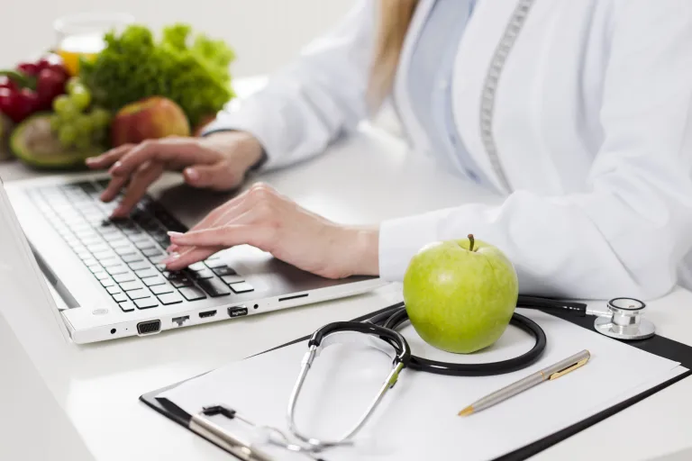 Dietetyka kliniczna | Studia podyplomowe we Wrocławiu | Uniwersytet WSB Merito we Wrocławiu: Kobieta pracująca przy laptopie ze stetoskopem 