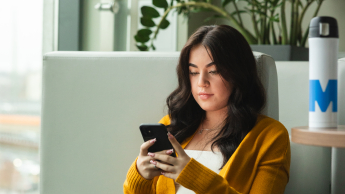 Tworzenie aplikacji internetowych i mobilnych | Studia podyplomowe we Wrocławiu | Uniwersytet WSB Merito we Wrocławiu: studentka używająca telefonu