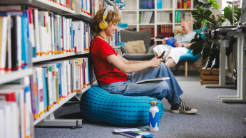 Zintegrowana terapia i  wsparcie osób z  ADHD | Studia podyplomowe we Wrocławiu | Uniwersytet WSB Merito we Wrocławiu: studentka słuchająca muzyki w bibliotece