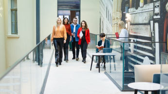 Cyfryzacja, współpraca i bezpieczeństwo pracy – praktyczne kompetencje specjalistów Publicznych Służb Zatrudnienia | Uniwersytet WSB Merito we Wrocławiu: uczestnicy studiów podyplomowych idący korytarzem