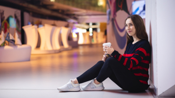 Scrum Master | Uniwersytet WSB Merito we Wrocławiu: studentka siedząca na ziemi i pijąca kawę