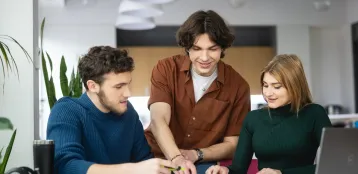 Strona główna | Uniwersytet WSB Merito we Wrocławiu: trzy osoby przy stole pracują wspólnie nad projektem