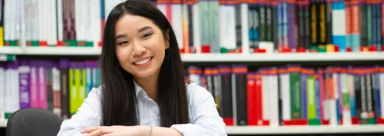 Centrum Współpracy Międzynarodowej | Uniwersytet WSB Merito we Wrocławiu: studentka w bibliotece pozująca do zdjęcia