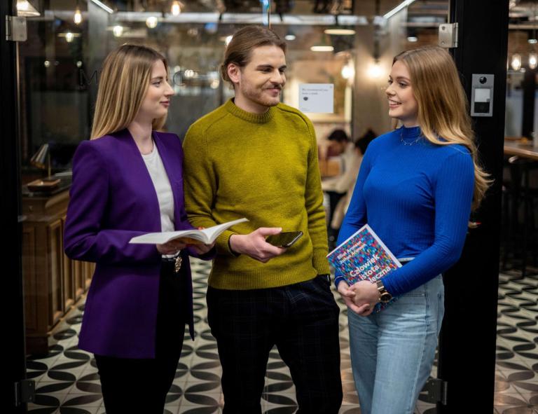 Pośrednictwo pracy | Uniwersytet WSB Merito we Wrocławiu: Główna grafika: Wrocław - pośrednictwo pracy - grupa ludzi rozmawiająca w ciemnym korytarzu