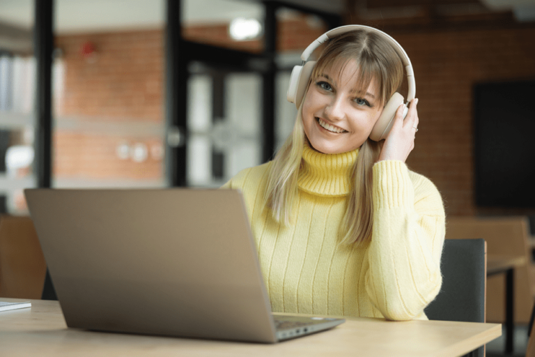 Sztuczna inteligencja w zastosowaniach biznesowych | Studia I stopnia we Wrocławiu | Uniwersytet WSB Merito we Wrocławiu: Dziewczyna w słuchawka i z laptopem uśmiecha się