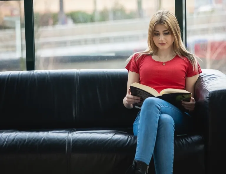 Project management | Studia II stopnia we Wrocławiu | Uniwersytet WSB Merito we Wrocławiu: studentka siedząca na kanapie i czytająca książkę