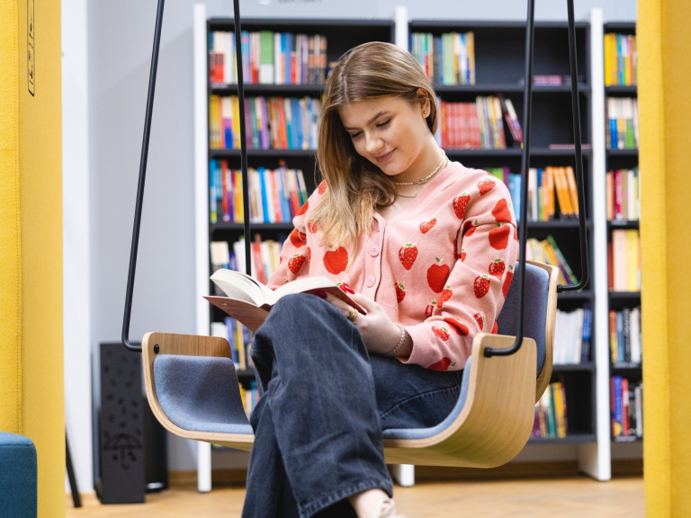 Pedagogika przedszkolna i wczesnoszkolna | Studia jednolite magisterskie we Wrocławiu | Uniwersytet WSB Merito we Wrocławiu: studentka czytająca książkę w bibliotece