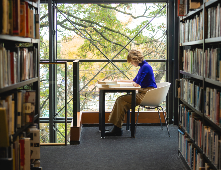 Język niemiecki w środowisku biznesowym | Studia I stopnia we Wrocławiu | Uniwersytet WSB Merito we Wrocławiu: studentka czytająca książkę w bibliotece