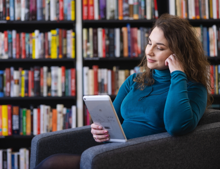 Zarządzanie jakością | Studia podyplomowe we Wrocławiu | Uniwersytet WSB Merito we Wrocławiu: uczestniczka studiów podyplomowych czytająca książkę w bibliotece