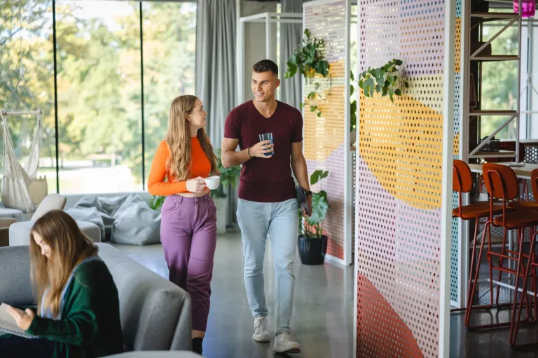Nasze wartości | Uniwersytet WSB Merito we Wrocławiu: Główna grafika: poznaj WSB Merito Wrocław - studentka i student idą korytarzem uczelni