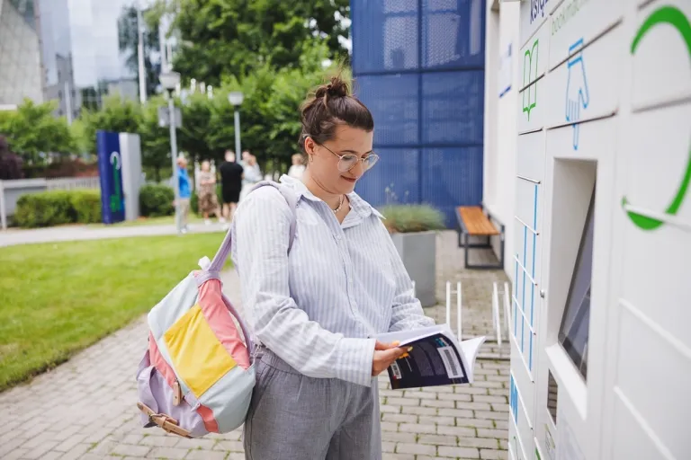 Logistyka humaniatarna | Studia I stopnia we Wrocławiu | Uniwersytet WSB Merito we Wrocławiu: studentka odbierająca książkę z książkomatu